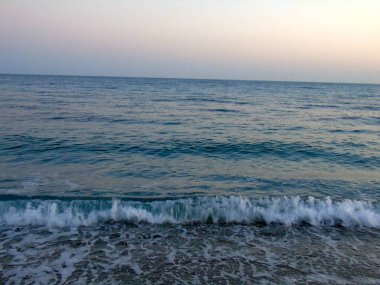 Genova, İtalya - 15.03.2019: Güzel kırmızı ve mavi gökyüzü, arka planda bazı şaşırtıcı bulutlar ve deniz üzerinde eski kayalar ile Genova denizi üzerinde bahar günlerinde gün batımı inanılmaz bir başlık.