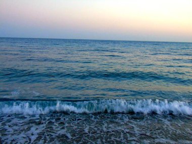 Genova, İtalya - 15.03.2019: Güzel kırmızı ve mavi gökyüzü, arka planda bazı şaşırtıcı bulutlar ve deniz üzerinde eski kayalar ile Genova denizi üzerinde bahar günlerinde gün batımı inanılmaz bir başlık.