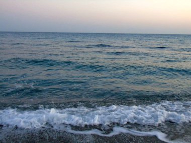 Genova, İtalya - 15.03.2019: Güzel kırmızı ve mavi gökyüzü, arka planda bazı şaşırtıcı bulutlar ve deniz üzerinde eski kayalar ile Genova denizi üzerinde bahar günlerinde gün batımı inanılmaz bir başlık.