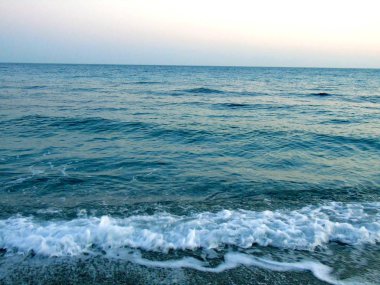 Genova, İtalya - 15.03.2019: Güzel kırmızı ve mavi gökyüzü, arka planda bazı şaşırtıcı bulutlar ve deniz üzerinde eski kayalar ile Genova denizi üzerinde bahar günlerinde gün batımı inanılmaz bir başlık.