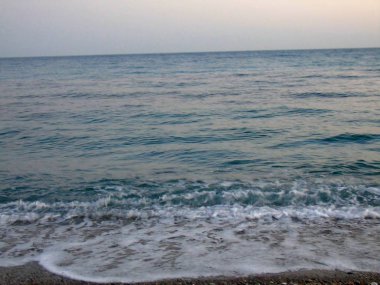 Genova, İtalya - 15.03.2019: Güzel kırmızı ve mavi gökyüzü, arka planda bazı şaşırtıcı bulutlar ve deniz üzerinde eski kayalar ile Genova denizi üzerinde bahar günlerinde gün batımı inanılmaz bir başlık.