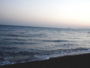 Genova, İtalya - 15.03.2019: Güzel kırmızı ve mavi gökyüzü, arka planda bazı şaşırtıcı bulutlar ve deniz üzerinde eski kayalar ile Genova denizi üzerinde bahar günlerinde gün batımı inanılmaz bir başlık.