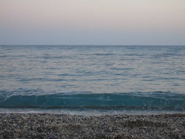 Genova, İtalya - 15.03.2019: Güzel kırmızı ve mavi gökyüzü, arka planda bazı şaşırtıcı bulutlar ve deniz üzerinde eski kayalar ile Genova denizi üzerinde bahar günlerinde gün batımı inanılmaz bir başlık.