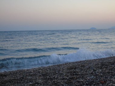 Genova, İtalya - 15.03.2019: Güzel kırmızı ve mavi gökyüzü, arka planda bazı şaşırtıcı bulutlar ve deniz üzerinde eski kayalar ile Genova denizi üzerinde bahar günlerinde gün batımı inanılmaz bir başlık.