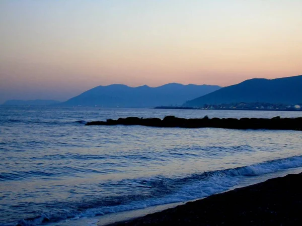 Genova, İtalya - 15.03.2019: Güzel kırmızı ve mavi gökyüzü, arka planda bazı şaşırtıcı bulutlar ve deniz üzerinde eski kayalar ile Genova denizi üzerinde bahar günlerinde gün batımı inanılmaz bir başlık.