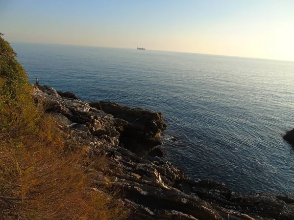 ジェノバ イタリア 2019 美しい赤と青の空とジェノバの海の上に春の日の夕日の素晴らしいキャプション 背景にいくつかの素晴らしい雲と海の上の古い岩 — ストック写真