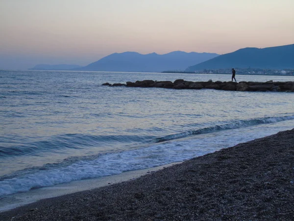Genova, İtalya - 15.03.2019: Güzel kırmızı ve mavi gökyüzü, arka planda bazı şaşırtıcı bulutlar ve deniz üzerinde eski kayalar ile Genova denizi üzerinde bahar günlerinde gün batımı inanılmaz bir başlık.