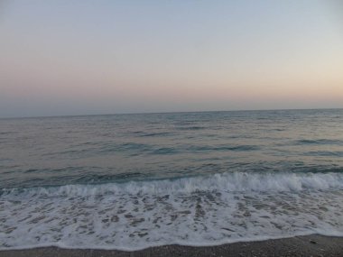 Genova, İtalya - 15.03.2019: Güzel kırmızı ve mavi gökyüzü, arka planda bazı şaşırtıcı bulutlar ve deniz üzerinde eski kayalar ile Genova denizi üzerinde bahar günlerinde gün batımı inanılmaz bir başlık.