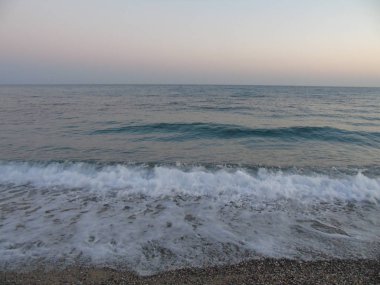 Genova, İtalya - 15.03.2019: Güzel kırmızı ve mavi gökyüzü, arka planda bazı şaşırtıcı bulutlar ve deniz üzerinde eski kayalar ile Genova denizi üzerinde bahar günlerinde gün batımı inanılmaz bir başlık.