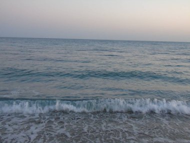 Genova, İtalya - 15.03.2019: Güzel kırmızı ve mavi gökyüzü, arka planda bazı şaşırtıcı bulutlar ve deniz üzerinde eski kayalar ile Genova denizi üzerinde bahar günlerinde gün batımı inanılmaz bir başlık.