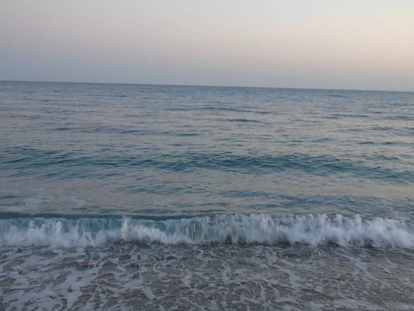 Genova, İtalya - 15.03.2019: Güzel kırmızı ve mavi gökyüzü, arka planda bazı şaşırtıcı bulutlar ve deniz üzerinde eski kayalar ile Genova denizi üzerinde bahar günlerinde gün batımı inanılmaz bir başlık.