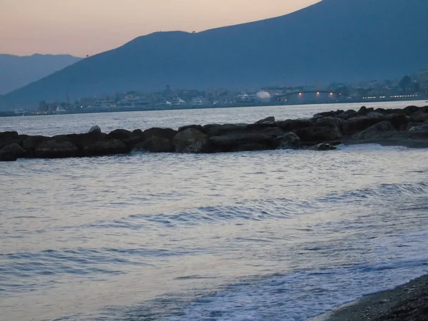 Genova, İtalya - 15.03.2019: Güzel kırmızı ve mavi gökyüzü, arka planda bazı şaşırtıcı bulutlar ve deniz üzerinde eski kayalar ile Genova denizi üzerinde bahar günlerinde gün batımı inanılmaz bir başlık.