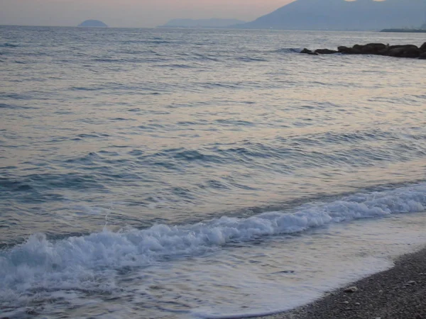 Genova, İtalya - 15.03.2019: Güzel kırmızı ve mavi gökyüzü, arka planda bazı şaşırtıcı bulutlar ve deniz üzerinde eski kayalar ile Genova denizi üzerinde bahar günlerinde gün batımı inanılmaz bir başlık.