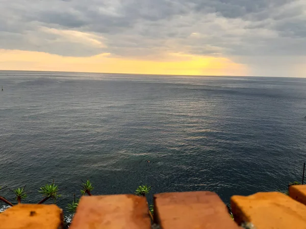 Genova, Italy - 06/18/2020: Beautiful photography of the sunset over the sea and clouds reflection on the water. Panoramic view to the ligurian coast in spring days.