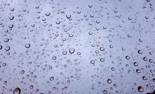 Beautiful photography of the waterdrop over the window. Indoor panoramic view to the city after rain.
