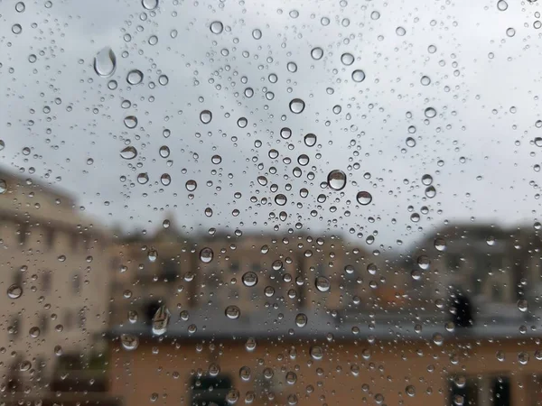 Beautiful photography of the waterdrop over the window. Indoor panoramic view to the city after rain.