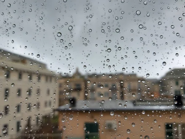 Beautiful photography of the waterdrop over the window. Indoor panoramic view to the city after rain.