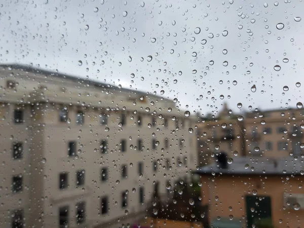 Beautiful photography of the waterdrop over the window. Indoor panoramic view to the city after rain.