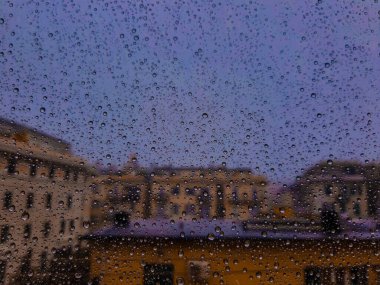 Pencerenin üzerindeki su damlasının güzel bir fotoğrafı. Yağmurdan sonra şehir için kapalı panoramik manzara.