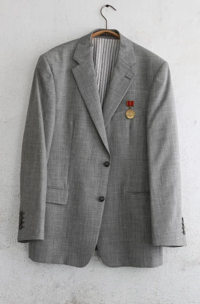 an old jacket with one Soviet medal hangs on a dirty wall