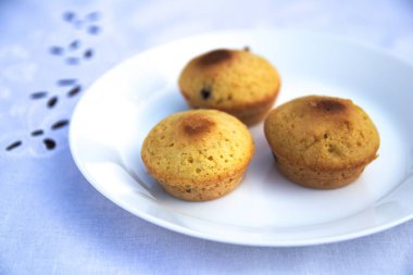 Muffins mavi bir masa örtüsü üzerinde beyaz bir tabak üzerinde yalan