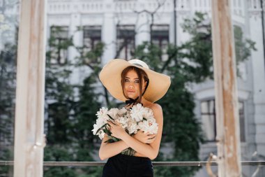 Kaliteli bir balkonda göğsünü taze şakayıkla kaplayan bir kızın zarif portresi ve başında siyah kurdeleli şık bir kamış.