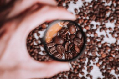 Büyüteç kahve çekirdekleri yukarıda tutan kişi el