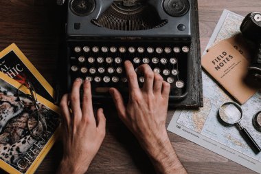 vintage daktilo makinesi, National Geographic dergi dünya haritası ile tablo üzerinde yazarak erkek ellerin üst görünümü 