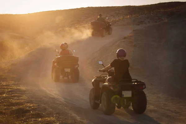 バック グラウンドで粉塵の多いカッパドキアの谷の日没の Atv を運転を楽しむ人々 — ストック写真