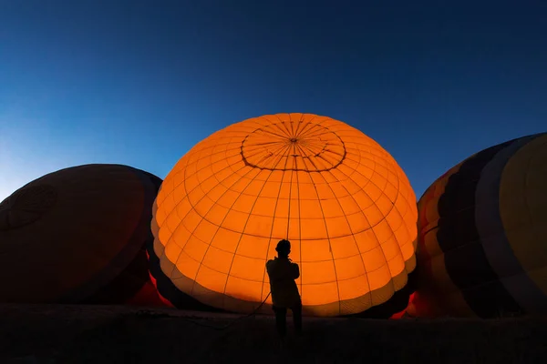 男子帮助在日出前放置一个热空气气球在背景美丽的蓝天 — 图库照片