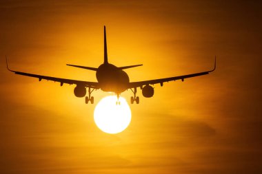 Güneşin arka planda güzel kırmızı bulutlar ile yakın air uçak silueti