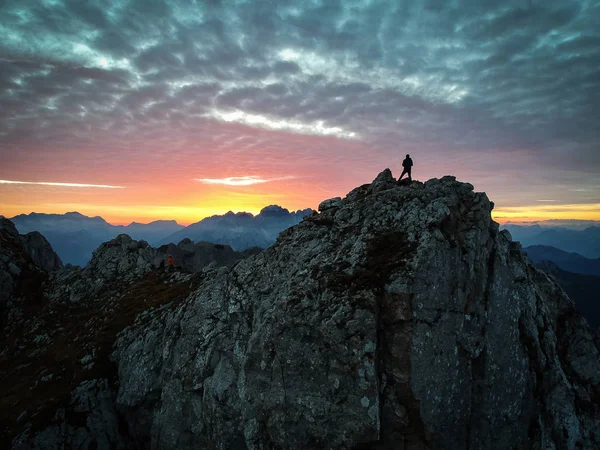 Silhouette eines Mannes, der den Sonnenuntergang in den Bergen mit c genießt — Stockfoto