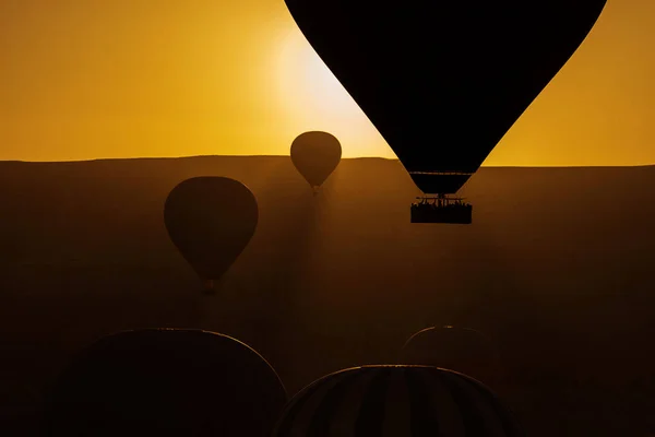 Silhouette of balloons with sunrise in background