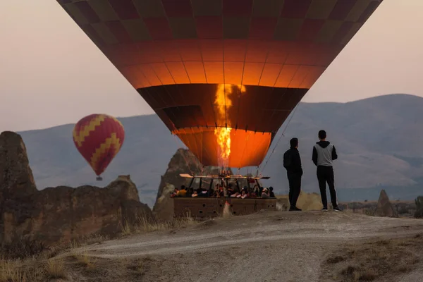 在土耳其卡帕多西亚日出时拍照和欣赏气球的人们 — 图库照片