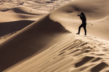 Sahra çölündeki kum tepelerinin fotoğraflarını çeken fotoğrafçı gün doğumunda güzel çizgiler ve renkler çiziyor. Merzouga, Fas