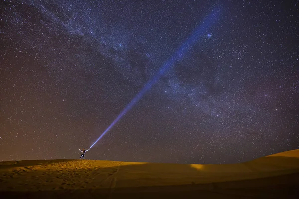 美しい天の川と満天の背景の星のデザートの途中で夜にランタンで遊んで男 — ストック写真