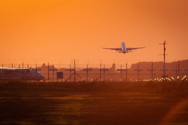 Uçak aynı zamanda arka planda kızıl gökyüzü ile batımında diğer kalkış ile çıkarmak hazırlanıyor yolda