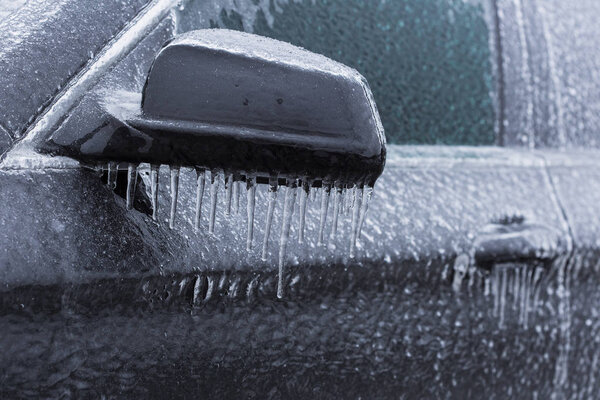 Frozen car hande in winter time with icicles