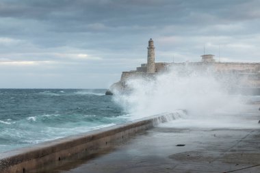 Güneş doğarken Malecon sokaklarında büyük dalgalar ve arka planda fırtına bulutları. Havana, Küba