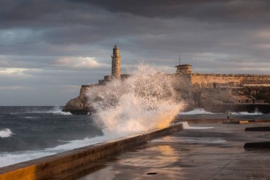 Güneş doğarken Malecon sokaklarında büyük dalgalar ve arka planda fırtına bulutları. Havana, Küba