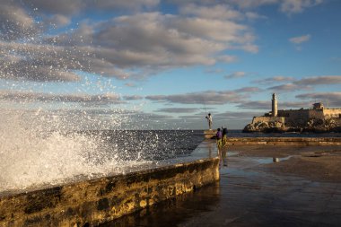 Güneş doğarken Malecon sokaklarında büyük dalgalar ve arka planda fırtına bulutları. Havana, Küba