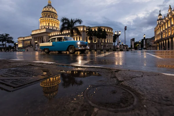 雨の時間に反射して背景にキャピトリオの建物とハバナの街の古い車 キューバ — ストック写真