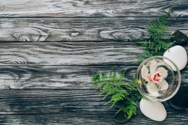 ahşap arka plan üzerinde görücü usulü çakıl, fern ve spa ve masaj için kase içinde orkide çiçek üstten görünüm