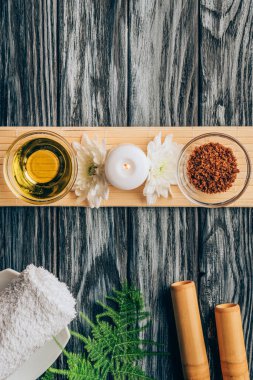 spa ve masaj için düzenlenmiş yağ, scrab, mum ve kasımpatı çiçekleri üstten görünüm ahşap masa üzerinde
