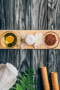 top view of arranged oil, scrab, candle and chrysanthemum flowers for spa and massage on wooden tabletop clipart