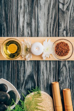 top view of arranged oil, scrab, candle and chrysanthemum flowers for spa and massage on wooden background clipart