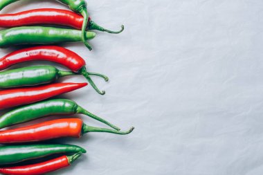 top view of red and green chili peppers on white tabletop clipart
