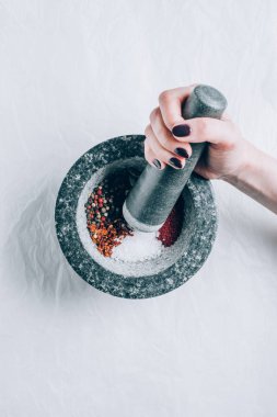 cropped image of woman grinding spices in mortar on white table clipart