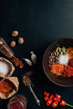 plaka, kavanoz ve kaşık farklı baharatlar üstten görünüm karanlık tablo