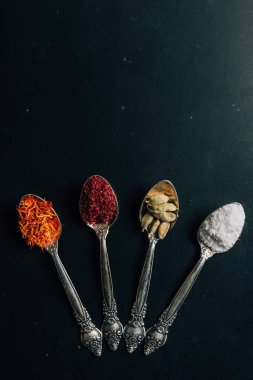 top view of spices in four spoons on table clipart
